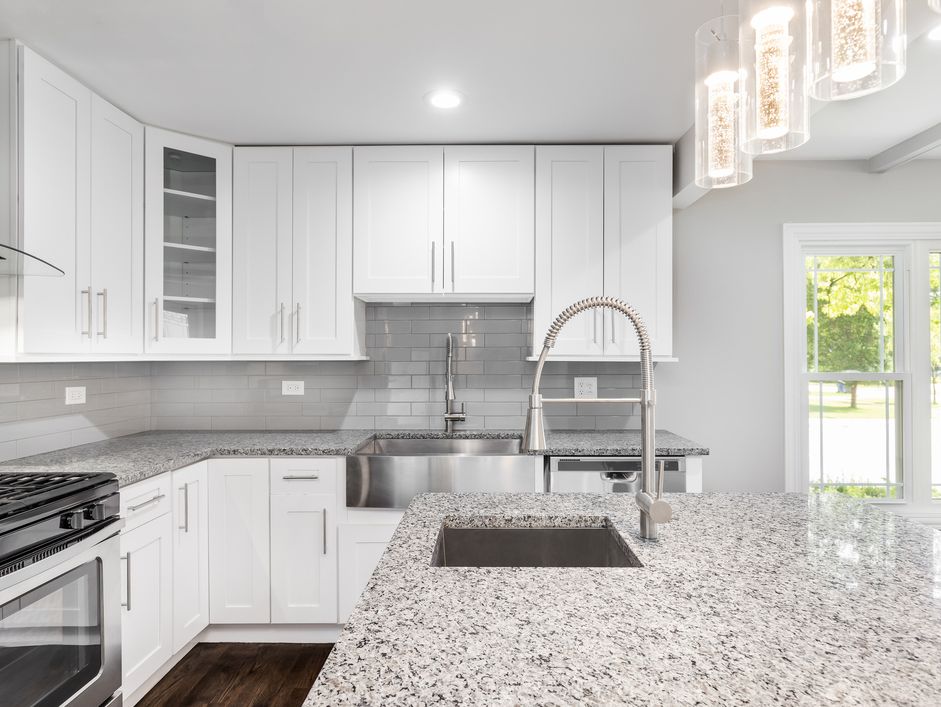 A-white-kitchen-with-a-stainless-steel-apron-sink,-granite-countertops-and-white-cabinets